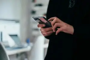 Person checking a phone, representing a vishing (voice phishing) social engineering attack on a business